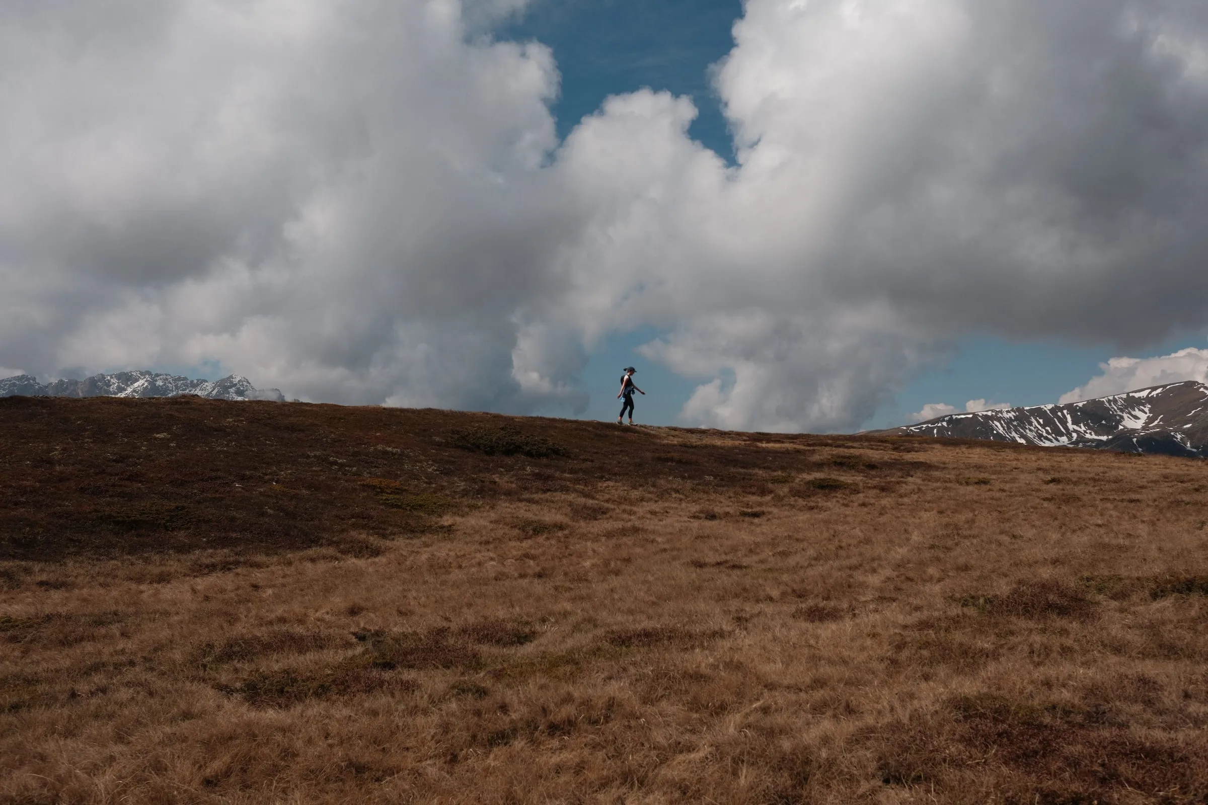 Wanderin auf dem weiten Wiesengrat unter tiefen Wolken